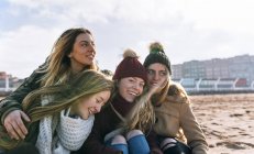Portrait of four young women on sandy beach in city — Stock Photo