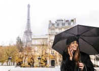 Paris, France, jeune femme utilisant son smartphone sous la pluie avec la Tour Eiffel en arrière-plan
. — Photo de stock