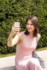 Ritratto di una giovane donna che fa selfie in panchina — Foto stock