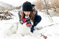 Leon, Spain, young beautiful woman giving a kiss to her dog in the snow — Stock Photo