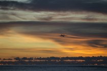 Indonésia, Bali, avião no céu e pôr do sol sobre o oceano — Fotografia de Stock