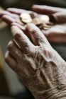 Las manos de la mujer mayor con monedas - foto de stock
