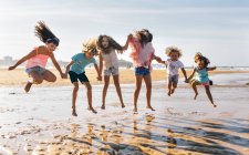 Groupe d'enfants sautant sur la plage, Gijn, Asturies, Espagne — Photo de stock