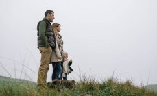 Spain, Asturias, Happy family looking views from meadow in a foggy day — Stock Photo