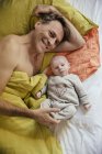 Pai abraçando na cama com bebê recém-nascido — Fotografia de Stock