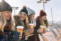 Four young women drinking take away coffee in winter — Stock Photo