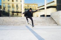 Skater boy saltar en el monopatín, vista del paisaje urbano en el fondo - foto de stock