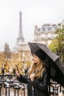 Paris, France, jeune femme utilisant son smartphone sous parapluie avec la Tour Eiffel en arrière-plan
. — Photo de stock