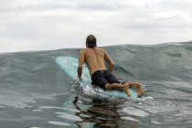 Indonesia, Java, man lying on surfboard on the sea — Stock Photo