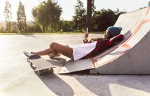 Gijn, Asturie, Spagna, skateboarder girl invia messaggi con il suo smartphone nello skatepark — Foto stock