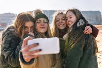 Quattro giovani donne che si fanno un selfie sulla spiaggia sabbiosa della città — Foto stock