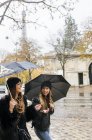 Париж, Франція, дві жінки туристів прогулянки в місті під дощем з Ейфелевої вежі у фоновому режимі. — стокове фото