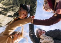 Quattro amici che uniscono le mani con cielo nuvoloso sullo sfondo — Foto stock