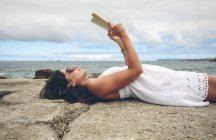 Женщина лежит на пирсе и читает книгу — стоковое фото