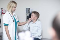 Femmina pedatrico esaminando ragazzo con un otoscopio — Foto stock