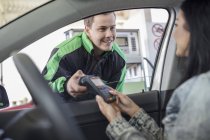 Female customer paying with debit card  with petrol attendant at the fuel station — Stock Photo