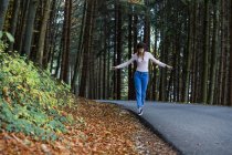 Jeune femme équilibrage au bord de la route dans les bois — Photo de stock