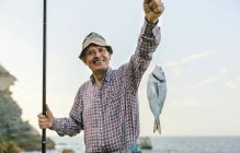 Щасливі старший чоловік тримає риби волосінь — стокове фото
