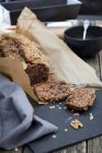 Pan de plátano parcialmente rebanado en papel envuelto en pizarra esquisada - foto de stock