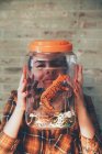 Funny woman pressing her face against jar with plastic animals — Stock Photo