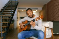 Giovane uomo che suona la chitarra a casa — Foto stock