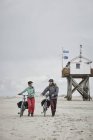 Jovem casal empurrando bicicletas na praia — Fotografia de Stock