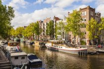 Paisagem da cidade velha de Amsterdã com barcos atracados pelo canal, Holanda — Fotografia de Stock