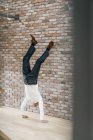 Homme d'affaires faisant un stand de main devant un mur de briques — Photo de stock