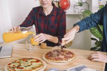 Giovane coppia mangiare pizza e bere succo di frutta a pranzo — Foto stock