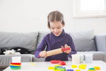 Little girl rolling modeling clay at home — Stock Photo