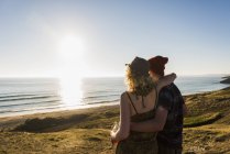 Rückansicht eines jungen Paares am Meer bei Sonnenuntergang — Stockfoto
