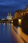 Germany, Cologne, lighted Cologne Cathedral and Hohenzollern Bridge — Stock Photo