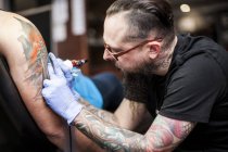 Татуировщик татуирует руку в студии — стоковое фото