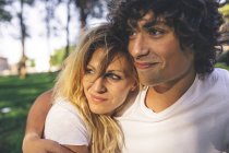 Souriant jeune couple embrassant dans le parc — Photo de stock