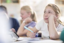 Studentessa in pensiero seduta alla scrivania durante la lezione in classe — Foto stock