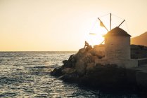 Grecia, Amorgos, Aegialis, silhouette dell'uomo seduto vicino al mulino a vento al tramonto — Foto stock