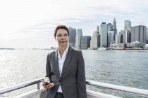 Pensive businesswoman standing on boat, Brooklyn, USA — Stock Photo