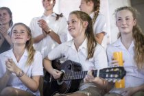 Female high school student playing guitar with group of school friends — Stock Photo
