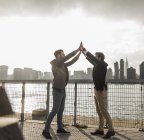 Deux hommes d'affaires donnant cinq à East River, New York, États-Unis — Photo de stock