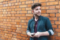 Felice giovane uomo con smartphone contro muro di rottura — Foto stock