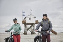 Lächelndes Paar schiebt Fahrräder am Strand — Stockfoto