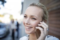 Retrato de una mujer sonriente hablando por teléfono celular - foto de stock
