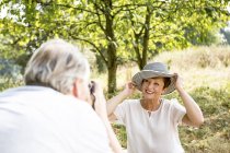 Senior-Mann fotografiert Frau mit Hut im Grünen — Stockfoto