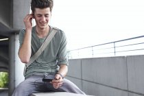 Усміхаючись підлітком зі стільникового телефону і навушників на відкритому повітрі — стокове фото