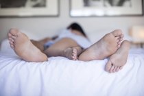 Masculino e feminino pés de casal deitado juntos na cama — Fotografia de Stock