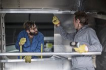 Dos hombres discutiendo dentro del contenedor de acero en fábrica - foto de stock