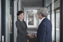 Empresario y empresaria estrechando la mano - foto de stock