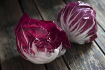 Vista de cerca de la hoja de lechuga roja y la cabeza en la superficie de madera oscura - foto de stock