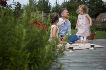 Padre bebiendo té con sus hijas en el jardín - foto de stock