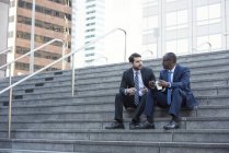 Due uomini d'affari seduti sulle scale a parlare — Foto stock